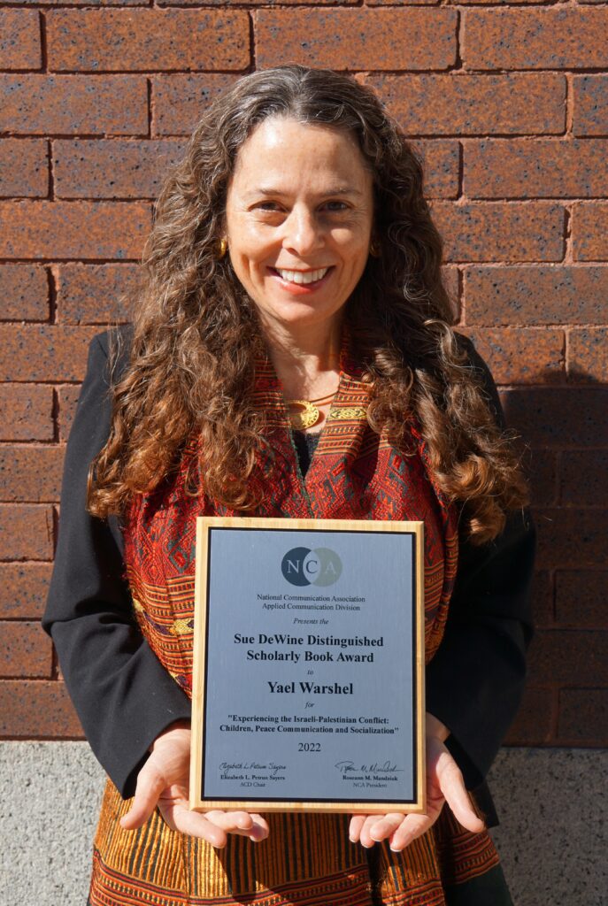 Dr. Yael Warshel holds her 2022 National Comunication Association Sue DeWine Distinguished Scholarly Book Award.